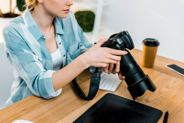 περικοπεί shot από νεαρή γυναίκα φωτογράφος που λειτουργεί με την κάμερα στο γραφείο - Φωτογραφία, εικόνα