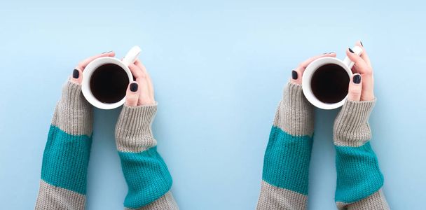 Hands holding a cup of freshly brewed black coffee, flat lay on blue background. - Foto, Bild