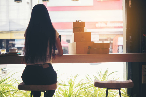 schöne Frau, die im Coffeeshop Verpackung auf Hintergrund arbeitet. Online-Shopping sme Unternehmer arbeiten junge Frauen glücklich nach einer neuen Bestellung von Kunden. E-Commerce-Online-Konzept. - Foto, Bild