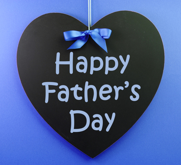 Happy Fathers Day message written on a black blackboard with blue ribbon against a blue background. - Photo, Image