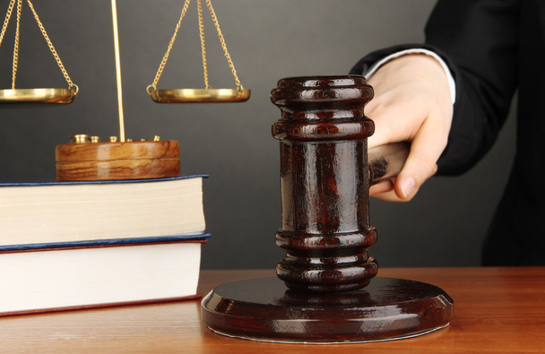 Judge's gavel in hand on grey background - Φωτογραφία, εικόνα