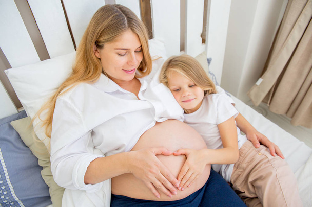 happy smiling pregnant mother hugging with her daughter at home - Fotografie, Obrázek