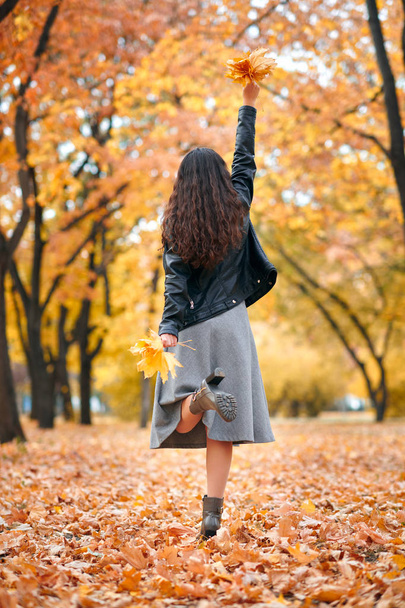 Mujer bonita posando con un montón de hojas de arce en el parque de otoño. Hermoso paisaje en temporada de otoño
. - Foto, Imagen