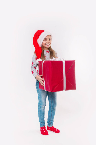 Smiling funny child in Santa red hat holding Christmas gift in hand. Christmas concept. - Fotoğraf, Görsel