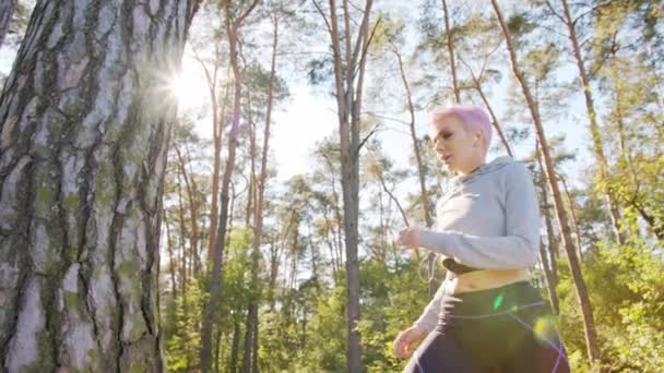 Jovencita con el pelo rosado estirándose en el bosque
 - Metraje, vídeo
