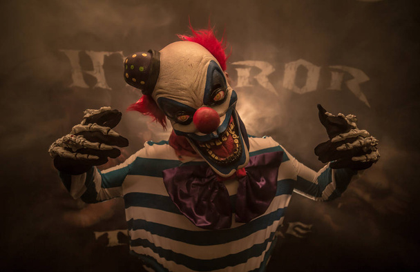 scary clown in mask posing against dark background - Photo, Image