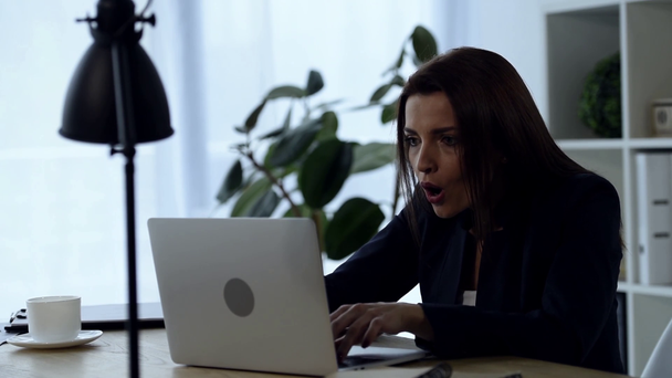 σοκαρισμένος επιχειρηματίας που εργάζονται για το laptop στο τραπέζι στο γραφείο  - Πλάνα, βίντεο