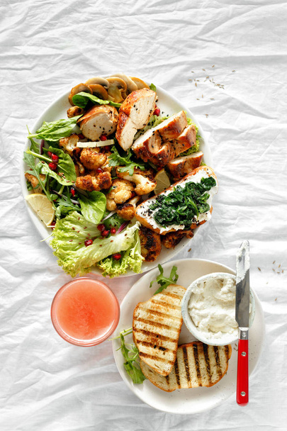 Lunch food bowl of fresh salad with chicken steak and fried cauliflower on white background with grapefruit fresh juice - Foto, immagini