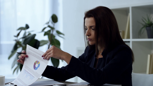 mujer de negocios adulta segura que trabaja con papeles en la mesa en la oficina moderna
  - Metraje, vídeo