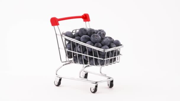 Supermarket trolley with fresh blueberries pile rotating on the turntable. Isolated on the white background. Close-up. Macro. - Séquence, vidéo
