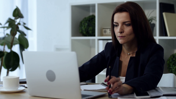 femme d'affaires adulte concentré travaillant sur ordinateur portable à la table dans le bureau
  - Séquence, vidéo