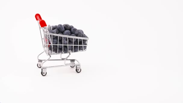 Shopping cart with fresh blueberries is moving forward. Isolated on the white background. Close-up. Macro. - 映像、動画