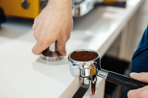 Barista hands holding portafilter and coffee tamper making an espresso coffee. - Foto, Imagem