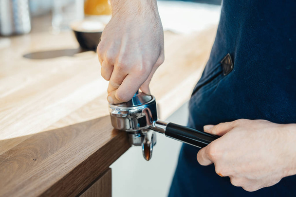 Barista hands holding portafilter and coffee tamper making an espresso coffee. - Foto, Imagem