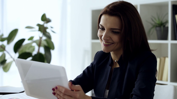 vrolijke zakenvrouw met behulp van digitale tablet aan tafel in de moderne kantoor  - Video