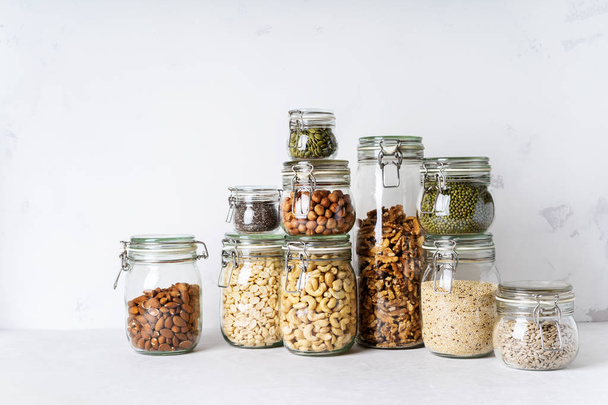 Collection of almonds, cashews, peanuts, hazelnuts, walnuts and Chia seeds, mung beans, quinoa, sunflower seeds in glass jars - Фото, зображення