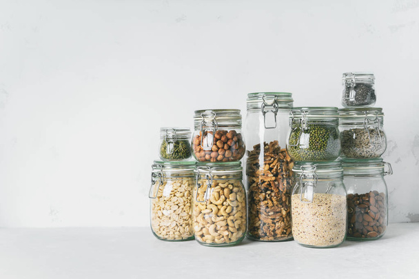 Collection of glass jars with almonds, cashews, peanuts, hazelnuts, walnuts and Chia seeds, mung beans, quinoa, sunflower seeds - Foto, Imagen