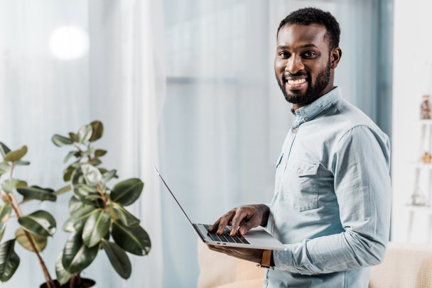 Afrikkalainen amerikkalainen freelancer hymyilee ja pitää kannettava tietokone
  - Valokuva, kuva