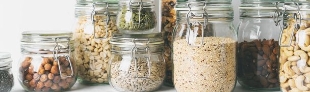 Glass jars with various nuts, beans and seeds on light background - Foto, Bild