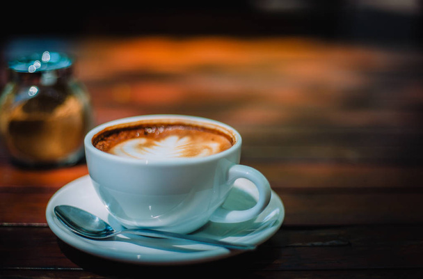 Kuuma kahvi latte cappuccino kierre vaahto puinen pöytä kahvilassa vintage väri sävy suodatin tausta. Kopioi tilaa tekstin
. - Valokuva, kuva