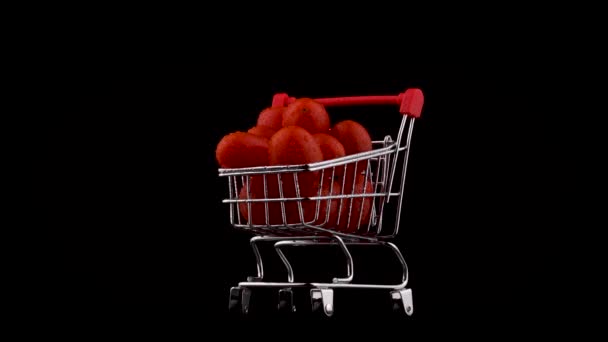 Shopping cart with red grape tomatoes pile with water drops. Rotating on the turntable. Isolated on the black background. Close-up. Macro. - Filmati, video