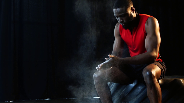スローモーションでジムでのトレーニングの前にタルク粉が付いている手をカバーするアフリカ系アメリカ人のスポーツマン - 映像、動画