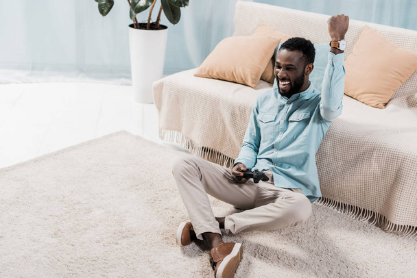 afro-amerikai ember játszik videó- és örvendezve nappali - Fotó, kép