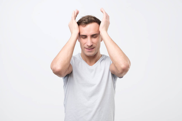 Αναστατώσει νεαρή ιταλική άνθρωπος δυστυχισμένος συμπιέζει το κεφάλι με τα χέρια, που υποφέρουν από πονοκέφαλο. - Φωτογραφία, εικόνα