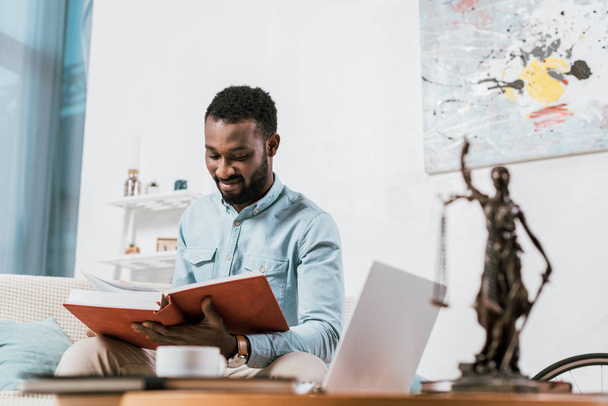 вибірковий фокус афроамериканського чоловіка читає книгу у вітальні
 - Фото, зображення