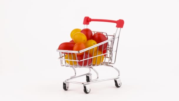 Supermarket trolley packed with red and yellow cherry tomatoes pile. Rotating on the turntable. Isolated on the white background. Close-up. Macro. - Video
