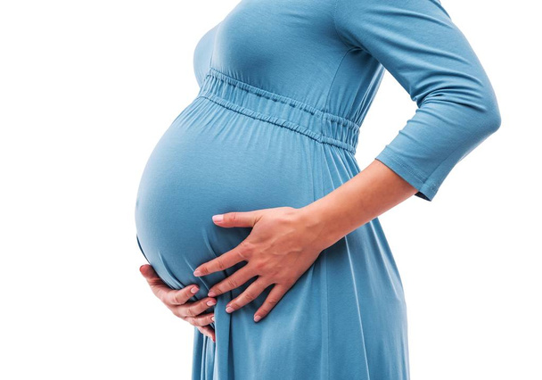 Mujer embarazada cogida de la mano en el vientre. Primer plano
. - Foto, imagen
