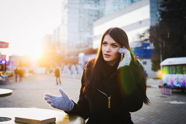 Portrait of angry woman talking on the phone at city centre - 写真・画像