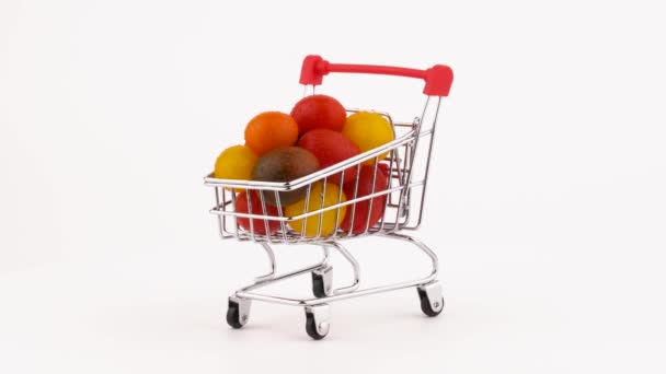Shopping cart packed with multicolored grape tomatoes pile with water drops. Rotating on the turntable. Isolated on the white background. Close-up. Macro. - Video