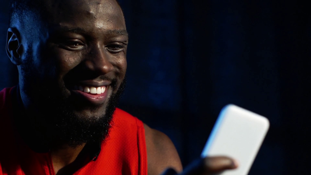 lächelnder afrikanisch-amerikanischer Mann mit Smartphone in Zeitlupe - Filmmaterial, Video