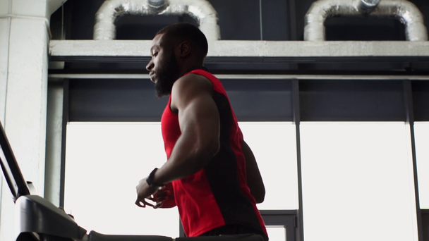 Afro-Amerikaanse sportman draait op loopband op sportschool in slow motion - Video