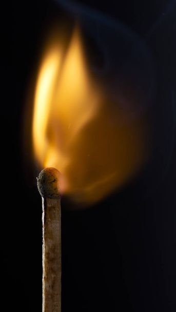 Burning wooden match with a red match head on a black background. Close up - Photo, Image