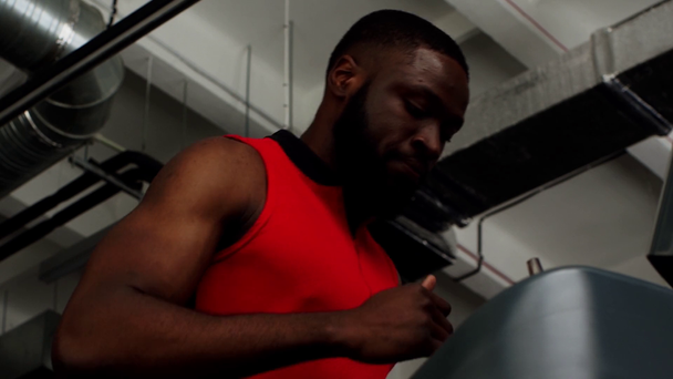 Afryki amerykański sportowiec działa na bieżni siłowni w zwolnionym tempie - Materiał filmowy, wideo