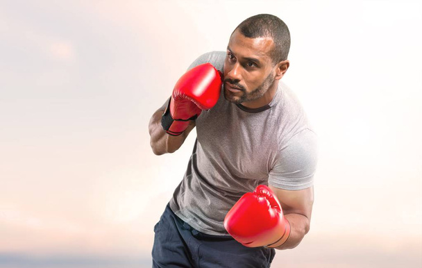 Strong sport man with boxing gloves fighting on sunset background - Photo, Image