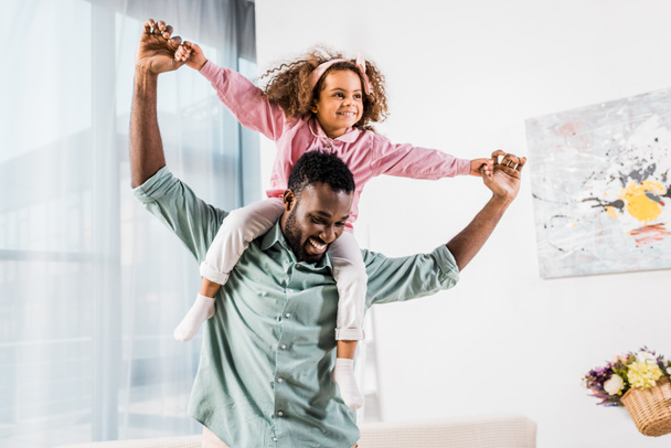 Afrikanisch-amerikanischer Mann spielt mit Tochter im Wohnzimmer - Foto, Bild