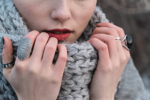 Dívka v podzimní nebo zimní park zabalila se v tlusté vlněné šátek pletený s velkými smyčky snaží zahřeje zmrzlé ruce - Fotografie, Obrázek