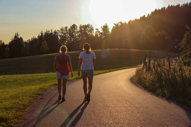two ladies on outdoor exercise at summer sunset evening in bavaria south germany countryside - 写真・画像