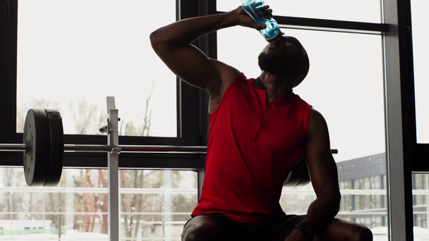 Αφρικανικός Αμερικανός αθλητής πόσιμο νερό μετά την άσκηση στο γυμναστήριο σε αργή κίνηση - Πλάνα, βίντεο