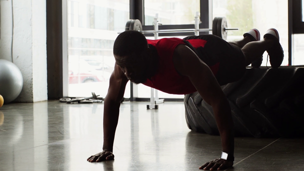 Afrikkalainen amerikkalainen urheilija tekee push ups kuntosalilla hidastettuna
 - Materiaali, video