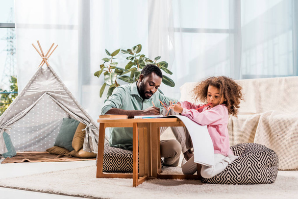 africano americano papá ayudar hija con dibujo en sala de estar
 - Foto, imagen