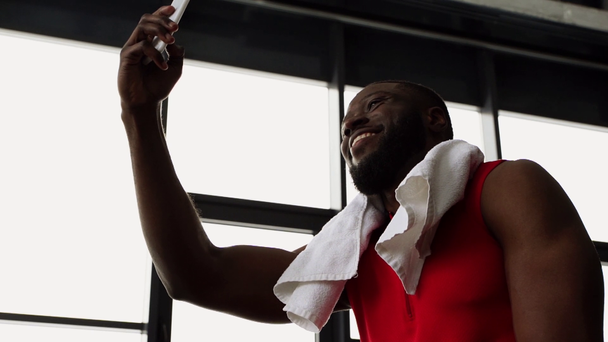 афроамериканський спортсмен з рушником за допомогою смартфона після тренування в спортзалі в повільному русі
 - Кадри, відео