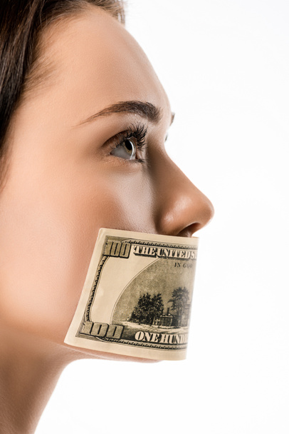 close-up view of woman with dollar banknote on mouth looking away isolated on white  - Фото, изображение