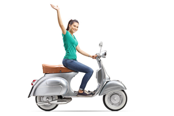 Young female riding a vintage scooter and waving isolated on white background - Фото, зображення