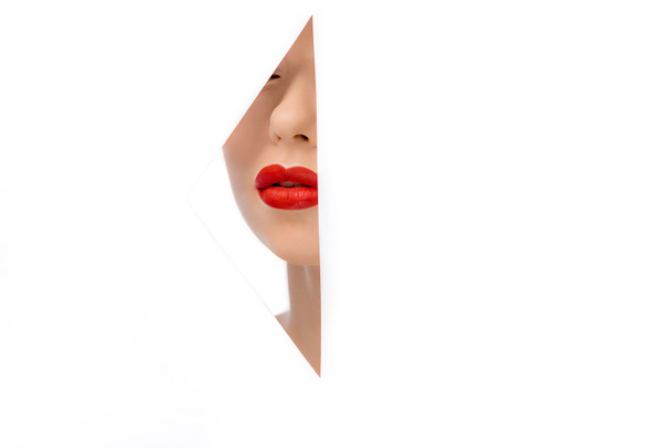όμορφη νεαρή γυναίκα με κόκκινα χείλη, προβάλετε μέσα από οπή στο λευκό - Φωτογραφία, εικόνα