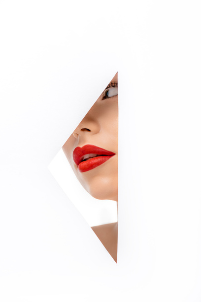 schöne junge Frau rote rote Lippen wegschauen, Blick durch Loch auf weiß - Foto, Bild