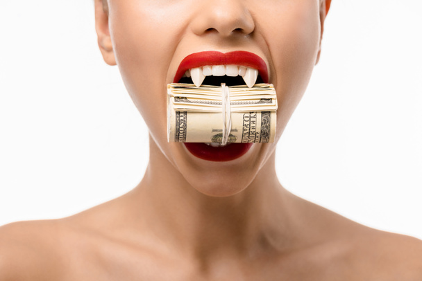 cropped shot of naked girl with vampire teeth holding rolled dollars in mouth isolated on white - Fotoğraf, Görsel